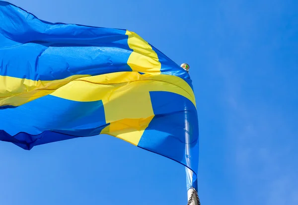 Vlag van Zweden wuiven in de wind op een blauwe hemelachtergrond — Stockfoto