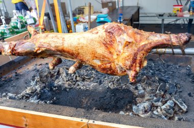 Sokak pazarındaki barbekü ızgarasının açık ateşinde kızartılmış bir tükürükte kuzu eti pişirmek. Geleneksel Sırp rostosu kuzu veya domuz barbeküsü