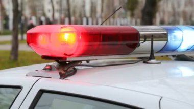 Polis aracının üstündeki kırmızı ve mavi ışıklara yakın çekim. Polis arabası yanıp sönüyor.