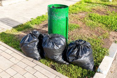 Çöp tenekesi ve sokakta plastik çöp torbaları.