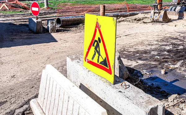 Under construction road sign on the closed road at the city street, stop sign. Caution symbol under construction, work in progress