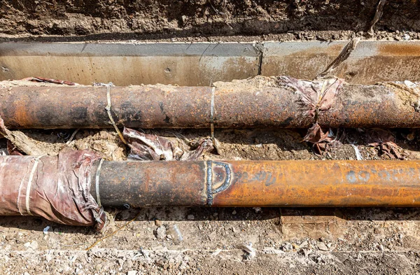 修理陈旧生锈的金属暖气管 在挖掘的壕沟深处的铁管上进行焊接工作 — 图库照片