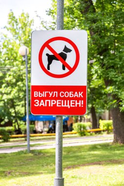 Parkta uyarı işareti var. Rusça metin: Köpek gezdirmek yasaktır