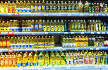 Samara, Rusya - 13 Haziran 2021: Süpermarkette satışa hazır çeşitli ayçiçekleri ve zeytin yağları. Şişe ayçiçeği, arka plan olarak zeytin yağı.