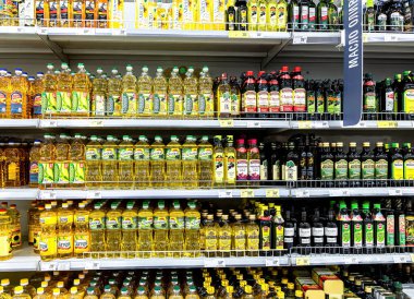 Samara, Rusya - 19 Haziran 2021: Süpermarkette satışa hazır çeşitli ayçiçekleri ve zeytin yağları. Şişe ayçiçeği, arka plan olarak zeytin yağı.