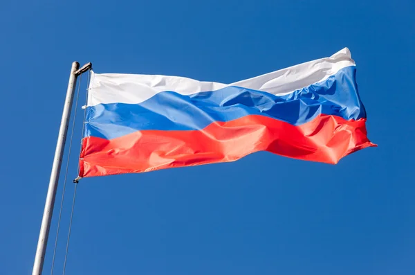 Russische vlag zwaaien in de wind over blauwe hemel — Stockfoto
