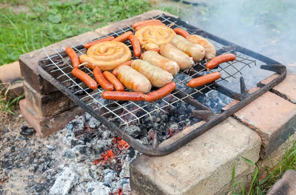 Barbecue avec de délicieuses saucisses grillées sur le gril — Photo