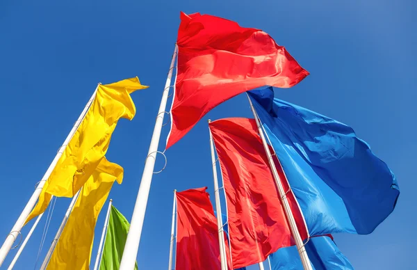 Drapeaux colorés agitant sur fond bleu ciel — Photo