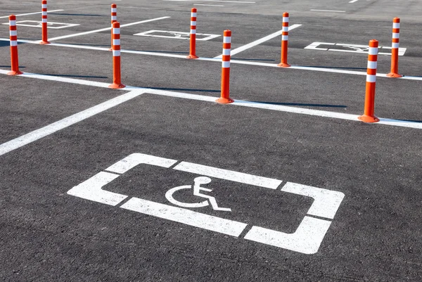 Icono de silla de ruedas blanca en un estacionamiento de asfalto gris — Foto de Stock