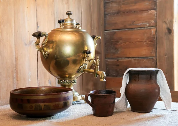 Old samovar and ceramic dishes on a table in a country house — Stock Photo, Image