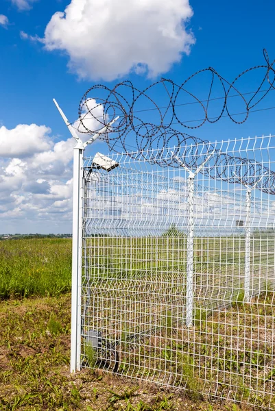 Hek met prikkeldraad op blauwe hemelachtergrond — Stockfoto