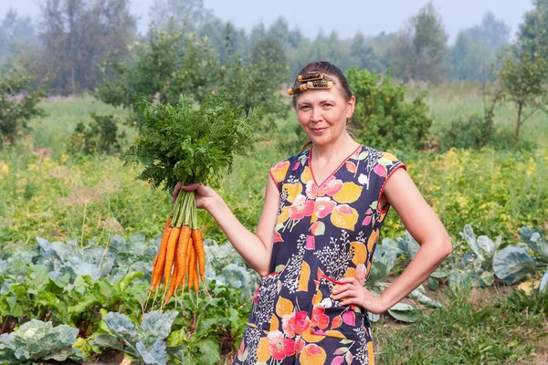 Ung kvinna med en stor bunt av morötter — Stockfoto