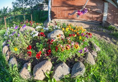 Salıncakta sallanan çocuklar güneşli summe flowerbed yakınındaki