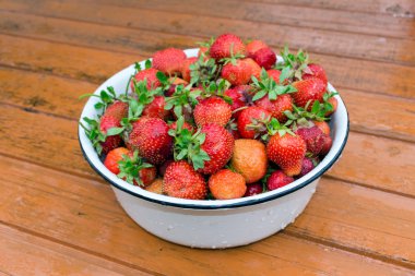 Ahşap masa üzerinde duran çilek ile emaye kase