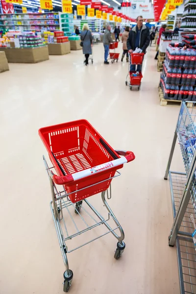 Carro de compras rojo vacío en el interior de la tienda Auchan —  Fotos de Stock