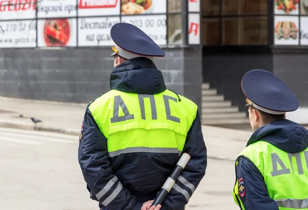Russische Polizisten stehen in lindfarbener Uniform am Straßenrand lizenzfreie Stockbilder