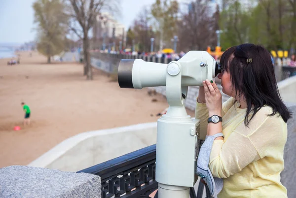 Mladá žena hledá prostřednictvím mince, binokulární — Stock fotografie