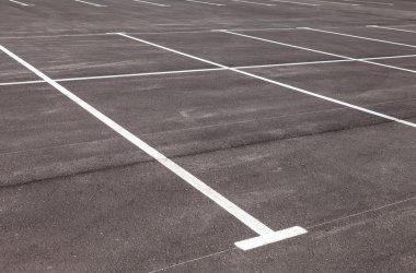 Bir gri asfalt otopark üzerindeki beyaz trafik işaretleri