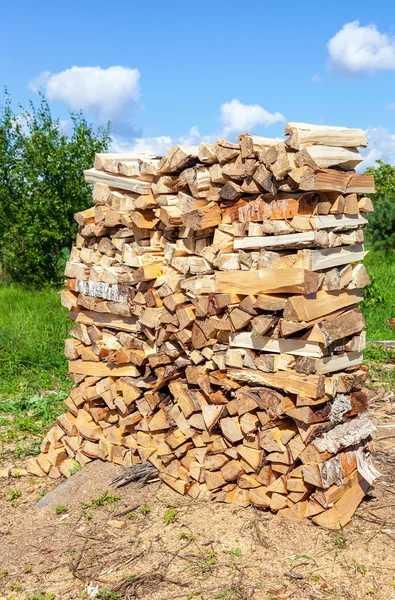 Hackad och staplade upp torr ved mot den blå himlen — Stockfoto