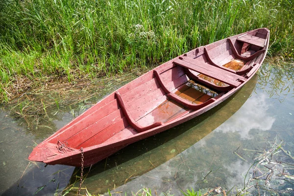 Old red wooden boat at the lake in summer day — Stock Photo, Image