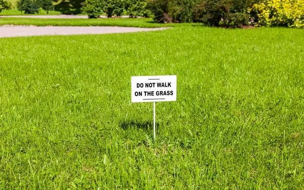 Anslagstavla på gräsmattan med texten "gå inte på gräset" — Stockfoto