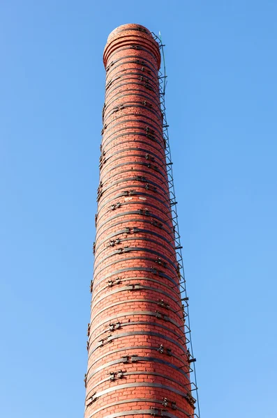 Alter roter Backsteinschornstein vor blauem Himmel — Stockfoto