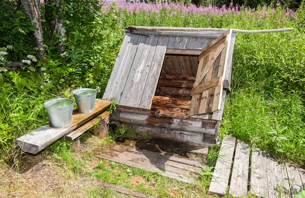 Village puits d'eau en bois avec la porte ouverte et un seau de wa — Photo