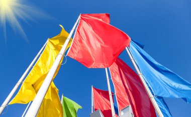 Mavi gökyüzü arka planında dalgalanan renkli bayraklar