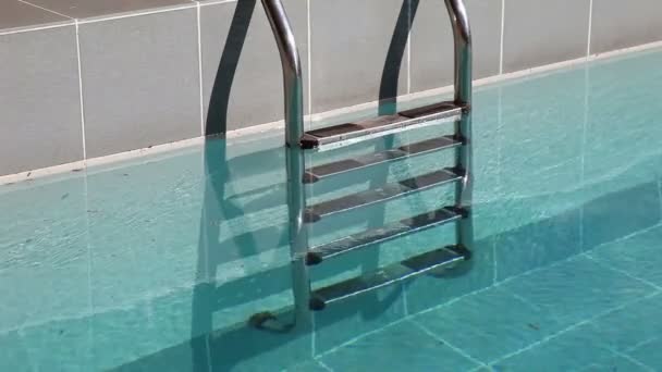 Water splashing in the outdoor swimming  pool with metal ladder — Stock Video