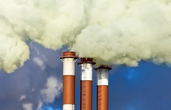 Industrial chimneys with smoke over blue sky — Stock Photo, Image