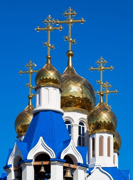 Golden domes of Russian orthodox church with cross against blue — Stock Photo, Image