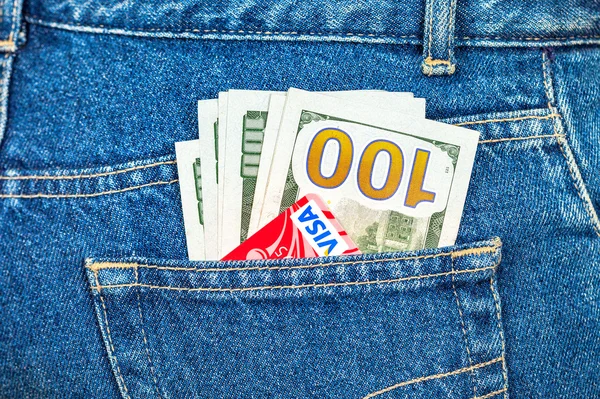 Tarjeta de crédito Visa con dólares estadounidenses que sobresalen de los pantalones vaqueros traseros — Foto de Stock