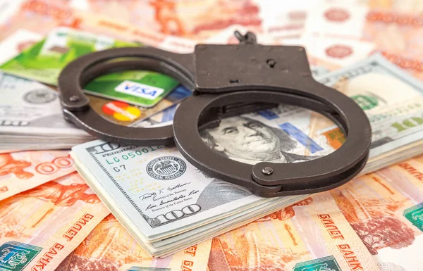 Steel handcuffs lying on a stack of dollar bills and credit card — Stock Photo, Image