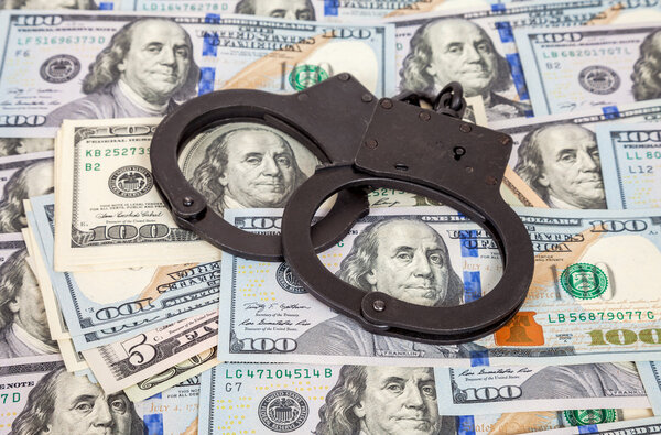 Steel handcuffs lying on the american dollar bills