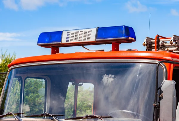 Närbild av blinkande blå Siren ljuset på taket av röd brandbil — Stockfoto