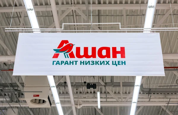 Auchan σήματος. Κείμενο στα ρωσικά: Auchan - χαμηλή τιμή εγγύηση — Φωτογραφία Αρχείου