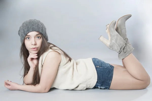 Young girl in a knitted hat lying on the floor — Stock Photo, Image