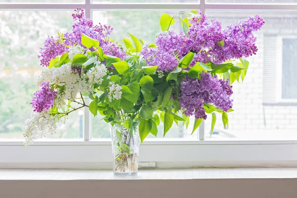 Lilac bouquet in vase on window — Stock Photo, Image