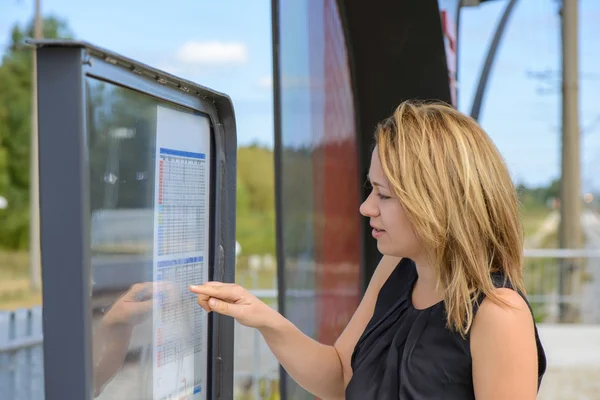 Kvinna som tittar en tidsplan i en station — Stockfoto