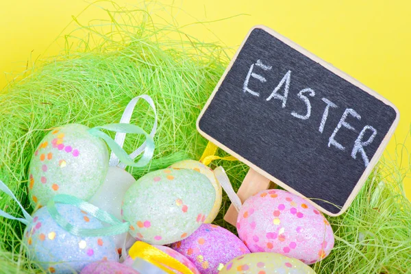 Ester eggs in nest with copy-space chalkboard — Stock Photo, Image
