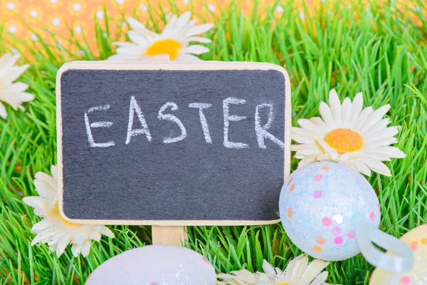 Easter eggs with blackboard on the grass — Stock Photo, Image