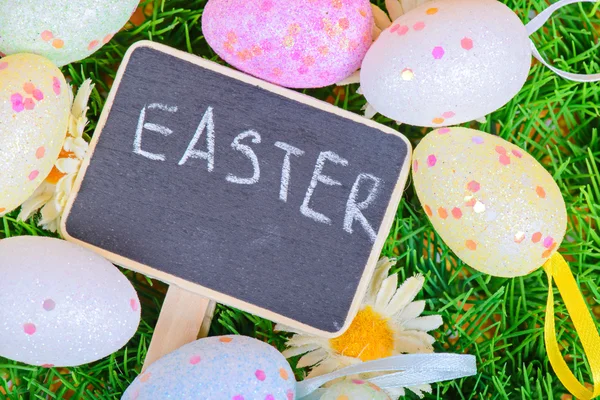 Easter eggs with chalkboard on the grass — Stock Photo, Image