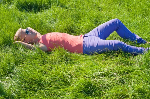 Jonge man in oranje liggend op het groene gras — Stockfoto