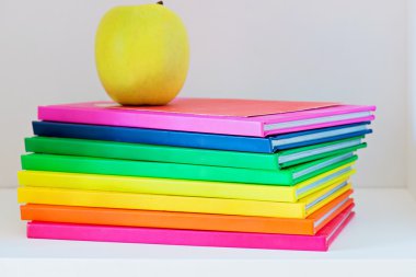 Okul kitapları bir yığın üstüne oturan elma