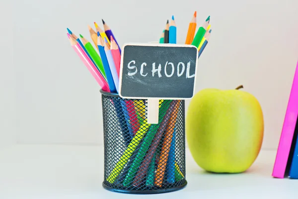 Lápices en el sostenedor, manzana amarilla y libro — Foto de Stock