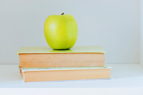 A yellow apple sitting on top of a stack of books