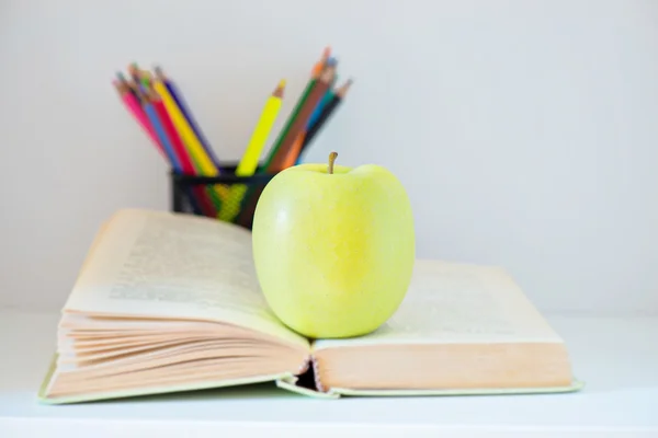 A yellow apple sitting on opened book — Stock Photo, Image