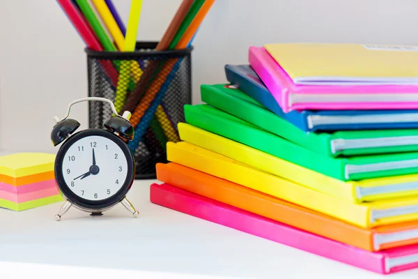 Black alarm clock and multi colored books in stack — Stock Photo, Image