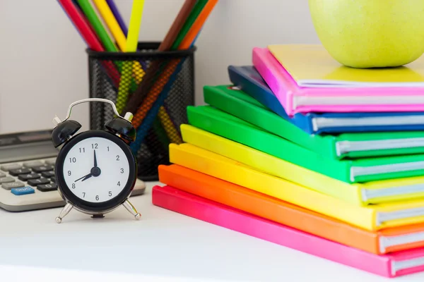 Black alarm clock and multi colored books in stack — Stock Photo, Image