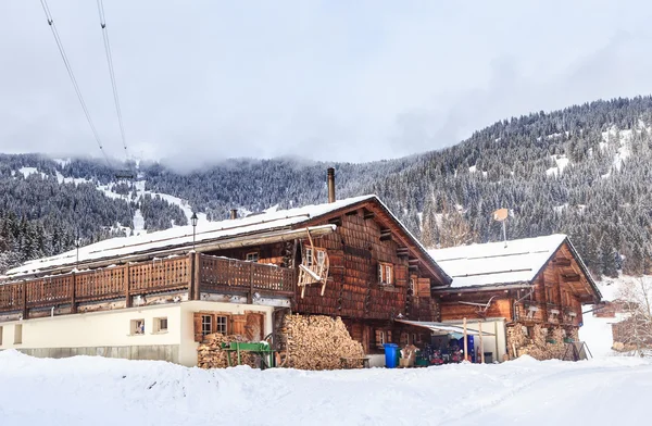 Maison de campagne avec un approvisionnement en bois de chauffage pour les montagnes d'hiver en arrière-plan — Photo